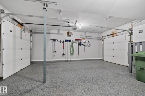Two-car garage featuring a speckled epoxy floor coating, two sectional overhead doors with track systems, and overhead lighting - 9 Greenfield Wynd, Fort Saskatchewan, AB - Indoor Photo Showing Garage