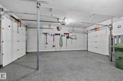 Two-car garage featuring a speckled epoxy floor coating, two sectional overhead doors with track systems, and overhead lighting - 