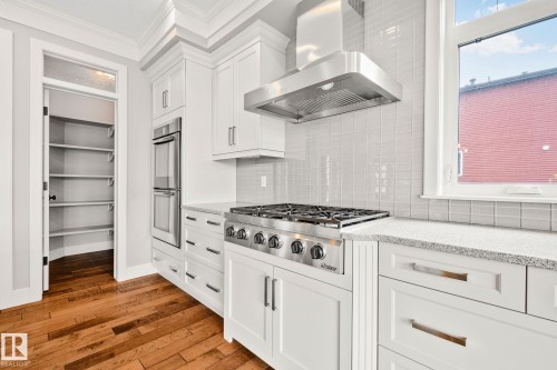Kitchen featuring a stainless steel gas range with a matching range hood, white shaker-style cabinetry, and light-toned countertops - 9 Greenfield Wynd, Fort Saskatchewan, AB - Indoor Photo Showing Kitchen With Upgraded Kitchen