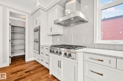 Kitchen featuring a stainless steel gas range with a matching range hood, white shaker-style cabinetry, and light-toned countertops - 
