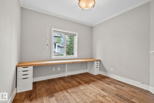 Room featuring wide plank wood-finish flooring and a built-in wood-finish desk with integrated white drawer units - 9 Greenfield Wynd, Fort Saskatchewan, AB - Indoor Photo Showing Other Room