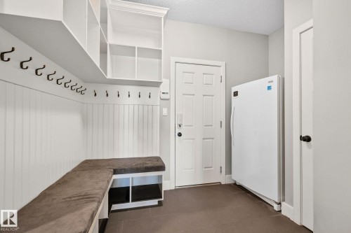 Mudroom featuring built-in white cabinetry, integrated bench seating with storage below, extensive wall hooks, and dark tile flooring - 9 Greenfield Wynd, Fort Saskatchewan, AB - Indoor Photo Showing Other Room