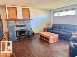 Living area featuring a tile-surround fireplace with a wood-burning insert and a wood mantel - 