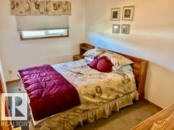 Bedroom featuring a wood-finish bed frame, built-in nightstands, a window with blinds and valance, and carpet flooring - 