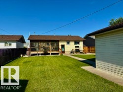 Expansive backyard featuring a screened-in porch, concrete patio, and a detached garage with vinyl siding - 