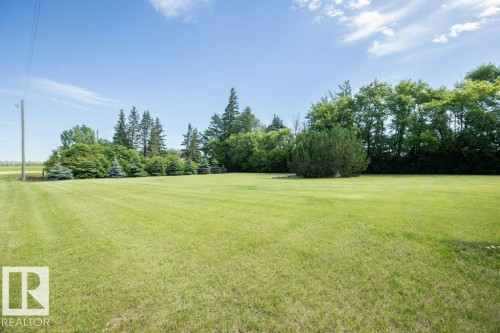 Expansive green lawn with a border of mature deciduous and evergreen trees - 25023 Twp Rd 612, Rural Westlock County, AB 