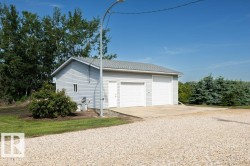 Detached garage structure featuring light gray siding, a gray shingle roof, two white garage doors, and a single white entry door - 