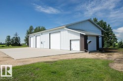 White metal-sided outbuilding with multiple overhead doors - 