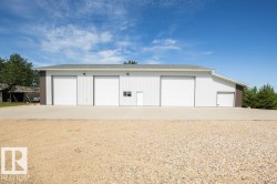 Metal-sided building featuring three large white garage doors and an additional smaller garage door - 