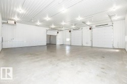 Expansive open-concept interior featuring concrete flooring and corrugated metal walls - 