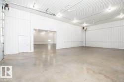 Large open room featuring concrete flooring and white corrugated panel walls - 