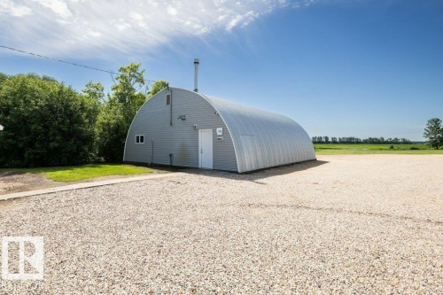 Quonset hut structure featuring corrugated metal siding and a white entry door - 25023 Twp Rd 612, Rural Westlock County, AB 