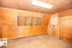 Interior space featuring plywood walls and ceiling, concrete flooring, and a fluorescent light fixture - 