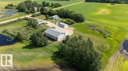 Expansive agricultural property featuring multiple outbuildings, a detached dwelling, and surrounding fields - 