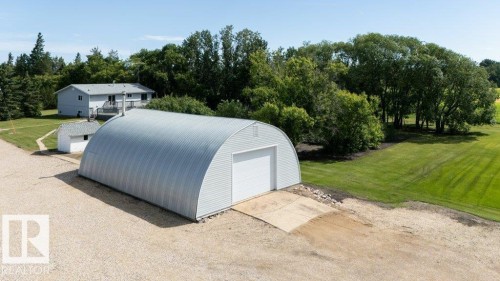 Quonset hut style structure with a corrugated metal exterior and a large white overhead door - 25023 Twp Rd 612, Rural Westlock County, AB 