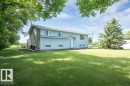 Spacious lot featuring a large grassy area, mature trees, and a two-story residence with light blue siding and white trim - 25023 Twp Rd 612, Rural Westlock County, AB 