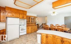 Kitchen featuring wood cabinetry, white appliances, laminate flooring, and an island with counter seating - 