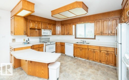 Kitchen featuring wood-finish cabinetry, white countertops, built-in appliances, and a window with horizontal blinds - 25023 Twp Rd 612, Rural Westlock County, AB 