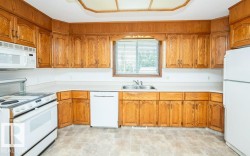 Kitchen featuring wood cabinetry, white countertops, white appliances, and a double-basin stainless steel sink - 