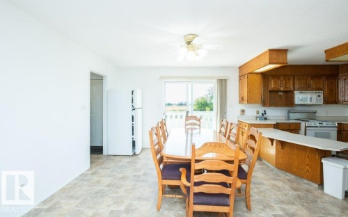 Open-concept dining area featuring wood-finish flooring, a ceiling fan with integrated lighting, and direct access to an outdoor space via sliding glass doors - 25023 Twp Rd 612, Rural Westlock County, AB 