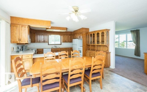 Open-concept kitchen and dining area featuring wood cabinetry, white countertops, and a white appliance package - 25023 Twp Rd 612, Rural Westlock County, AB 