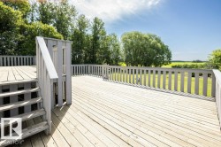 Expansive outdoor deck featuring wood plank flooring, a full perimeter railing, and integrated stairs - 