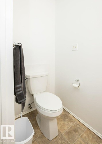 White toilet fixture in a compact space featuring neutral-toned tile flooring and white baseboards - 25023 Twp Rd 612, Rural Westlock County, AB 