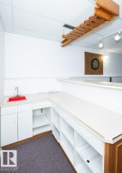 L-shaped countertop with integrated red sink, built-in white cabinetry, and open shelving - 