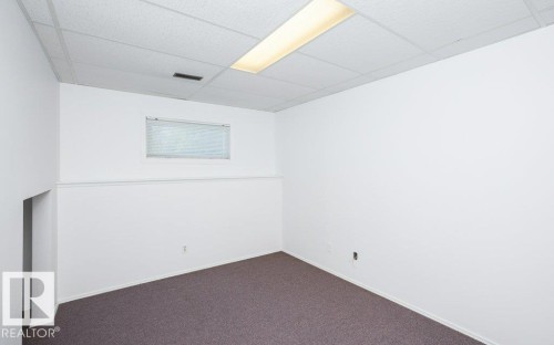 Carpeted room featuring white walls, a drop ceiling with recessed lighting, an egress window, and baseboard molding - 25023 Twp Rd 612, Rural Westlock County, AB 