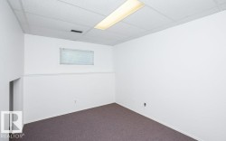 Carpeted room featuring white walls, a drop ceiling with recessed lighting, an egress window, and baseboard molding - 