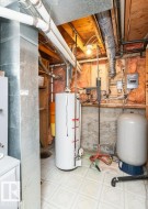 Utility space featuring a water heater, pressure tank, and exposed ceiling joists - 