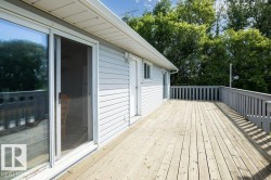 Expansive wood deck with painted railings, featuring a sliding glass door and an exterior entry door - 