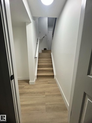 Interior staircase with wood-finish treads and risers, complemented by a white handrail with black supports - 3320 43 Street, Edmonton, AB 