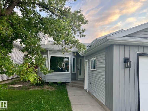 Contemporary home with mixed siding, featuring a prominent bay window, attached garage, and sleek exterior lighting - 3320 43 Street, Edmonton, AB 