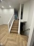 Central staircase with wood-finish treads, white risers, and modern black iron balusters - 3320 43 Street, Edmonton, AB 