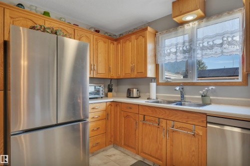 Kitchen featuring light wood cabinetry, white countertops, stainless steel refrigerator, and stainless steel sink with a window above - 184 Garwood Cres, Wetaskiwin, AB - Indoor Photo Showing Kitchen With Double Sink