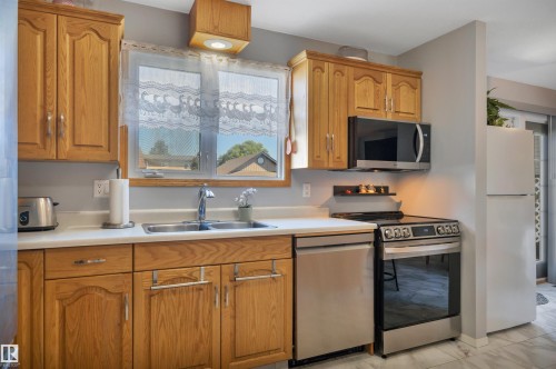Kitchen featuring wood cabinetry, a double basin stainless steel sink with a chrome faucet, and a white countertop - 184 Garwood Cres, Wetaskiwin, AB - Indoor Photo Showing Kitchen With Double Sink