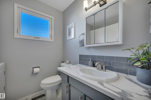 Bathroom featuring a white vanity with a marble-finish countertop, undermount sink, and a gray subway tile backsplash - 184 Garwood Cres, Wetaskiwin, AB - Indoor Photo Showing Bathroom