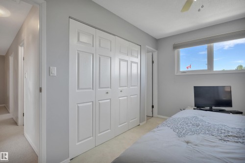 Bedroom featuring light gray wall paint, white bi-fold closet doors, white trim, light-colored carpet, and a window with a roller shade - 184 Garwood Cres, Wetaskiwin, AB - Indoor Photo Showing Bedroom