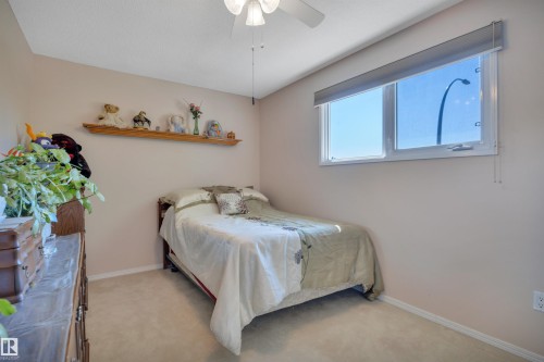 Carpeted room with a ceiling fan, a window with a roller shade, light-toned walls, and a wood-finish wall shelf - 184 Garwood Cres, Wetaskiwin, AB - Indoor Photo Showing Bedroom