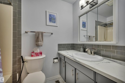 Bathroom featuring a vanity with a white countertop and integrated sink, gray cabinetry, and a mirrored medicine cabinet - 184 Garwood Cres, Wetaskiwin, AB - Indoor Photo Showing Bathroom