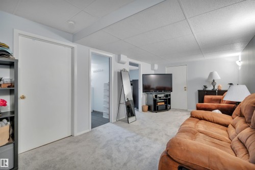 Carpeted recreation room featuring a drop ceiling, wall sconce lighting, and multiple interior doors - 184 Garwood Cres, Wetaskiwin, AB - Indoor