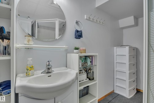 Compact bathroom featuring a white porcelain sink and wall-mounted circular mirror - 184 Garwood Cres, Wetaskiwin, AB - Indoor Photo Showing Bathroom