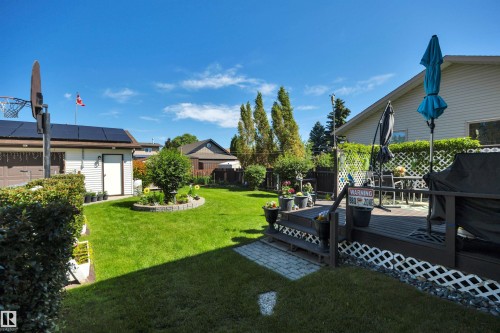 Expansive backyard featuring a large, manicured lawn, a multi-level deck, and a detached garage with solar panels - 184 Garwood Cres, Wetaskiwin, AB - Outdoor