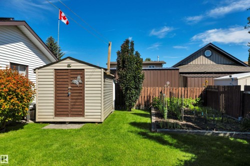Expansive backyard featuring a green lawn, a garden bed, and a storage shed with double doors - 184 Garwood Cres, Wetaskiwin, AB - Outdoor