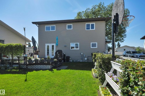 Expansive backyard featuring a manicured lawn, a multi-level wood deck, white lattice skirting, and mature perimeter hedging - 184 Garwood Cres, Wetaskiwin, AB - Outdoor With Deck Patio Veranda