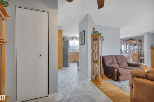 Entryway with bi-fold closet doors, featuring light gray walls, marble-look tile flooring, and wood-finish flooring - 184 Garwood Cres, Wetaskiwin, AB - Indoor With Fireplace
