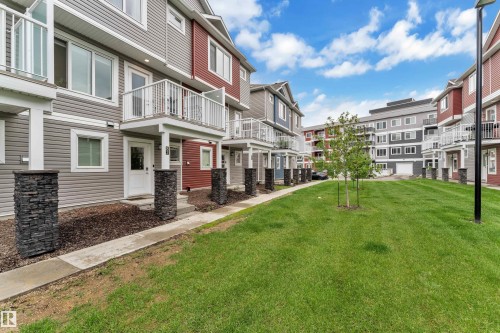 Modern townhome exteriors featuring horizontal siding in varied colors, stone pillar accents, and private balconies with white railings - 82 1816 Rutherford Road, Edmonton, AB 