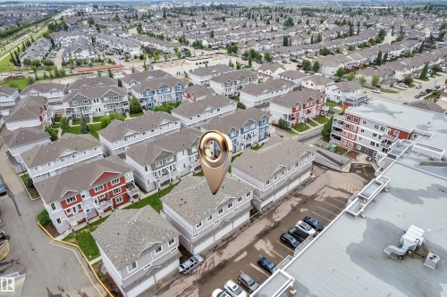 Aerial perspective showcasing a residential community with multi-story townhomes featuring light grey siding and dark roofs - 82 1816 Rutherford Road, Edmonton, AB 