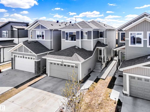 Contemporary multi-level home featuring grey siding, white trim, a covered porch entry, and an attached garage with a concrete driveway - 2435 12 Avenue, Edmonton, AB 